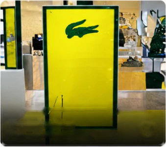 Painel em acrílico amarelo com o logotipo da Lacoste em vitrine