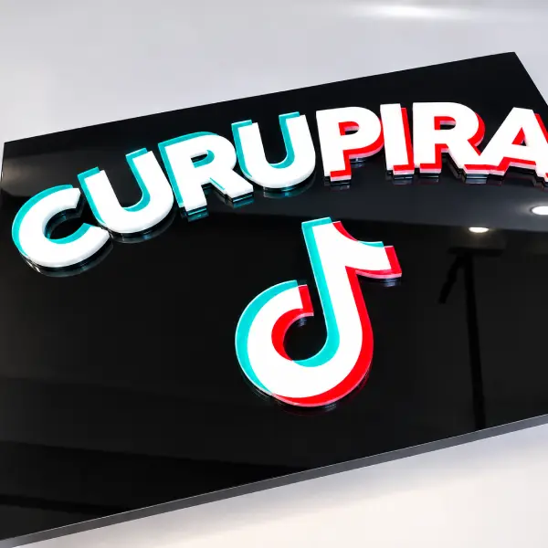 Letreiro "Curupira" com logotipo do TikTok em acrílico preto com letras em relevo